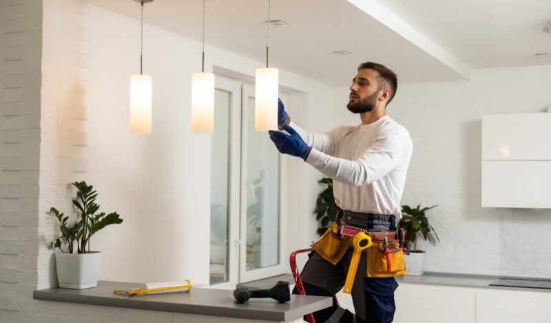 Electrician installs lamp lighting and spot loft style on ceiling Electrician installs lamp lighting and spot loft style on ceiling